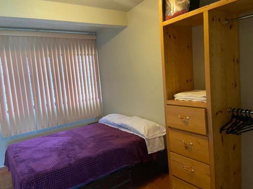 a bedroom with a purple bed and a dresser at Departamento con gran área verde in Zacatlán