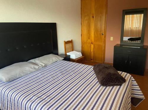 a bedroom with a bed with a blue and white striped blanket at Departamento con gran área verde in Zacatlán