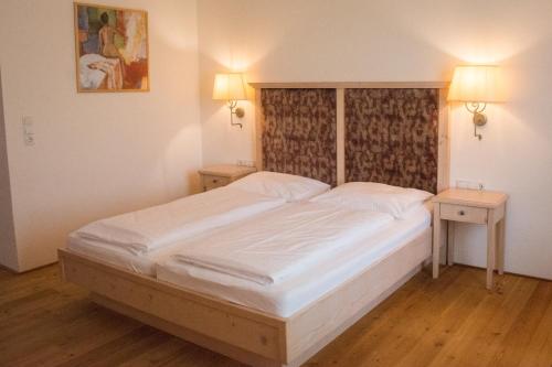 a bedroom with a large white bed with two tables at Hotel Krone Langenegg in Langenegg