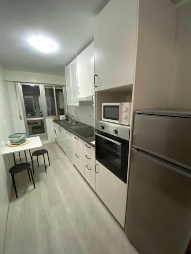 a kitchen with white cabinets and a stainless steel refrigerator at Céntrico, amplio y bonito apartamento en Cambados in Cambados