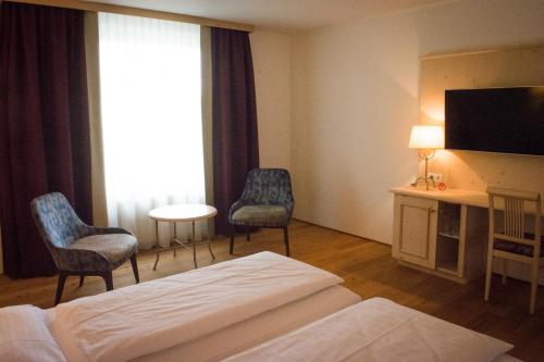 a hotel room with a bed and two chairs and a television at Hotel Krone Langenegg in Langenegg