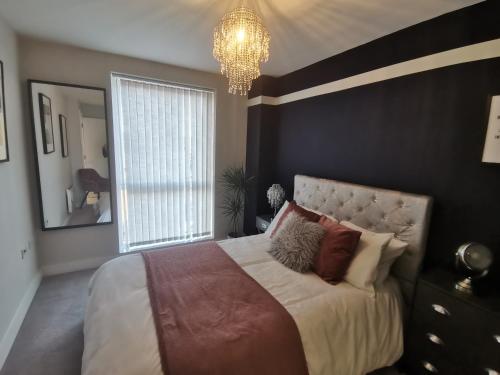 a bedroom with a large bed and a chandelier at The Metalworks by Ritual Stays in Hemel Hempstead