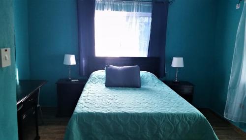 a blue bedroom with a bed and a window at Bailey's Bed and Breakfast in Runaway Bay