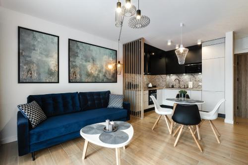 ein Wohnzimmer mit einem blauen Sofa und einer Küche in der Unterkunft Apartament Słoneczniki Cieplice in Jelenia Góra