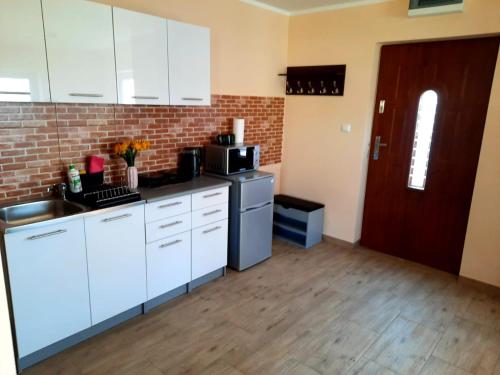a kitchen with white cabinets and a brick wall at Gajówka in Wünschelburg