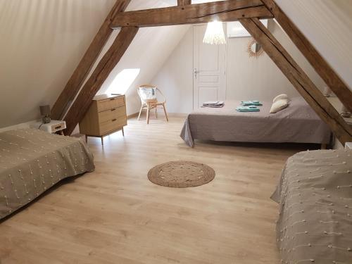 - une chambre mansardée avec 2 lits et une chaise dans l'établissement Maison Familiale proche Zoo de Beauval à Selles sur Cher GITE A l'Ombre du Saule, à Selles-sur-Cher