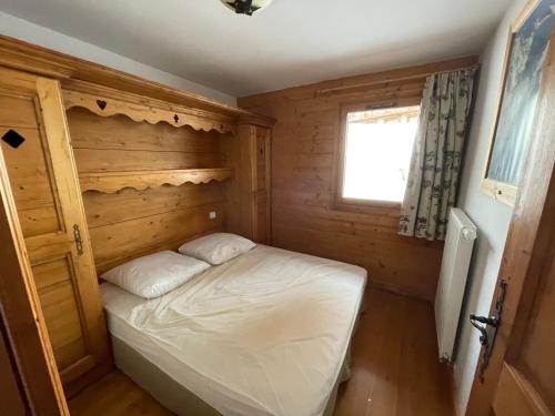 a small bedroom with a bed in a wooden cabin at Appartement ski aux pieds dans résidence premium piscine, sauna hamam in Les Menuires