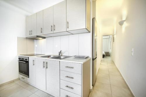 a kitchen with white cabinets and a sink and a hallway at Anius Apartments in Mýkonos City