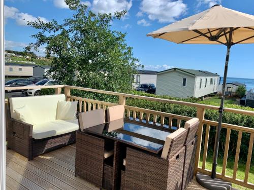 a table and chairs on a deck with an umbrella at Lydstep Beach BayView 3-Bedroom Holiday Home in Tenby