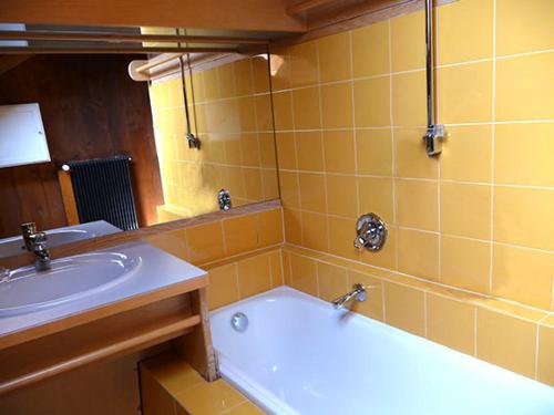 a yellow bathroom with a tub and a sink at ATI Appartamento stile Chalet dell 800 nel cuore di Ortisei in Ortisei
