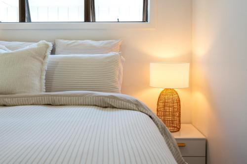 a bedroom with a bed with a lamp on a night stand at Bach 14 - Stay Waiheke in Blackpool
