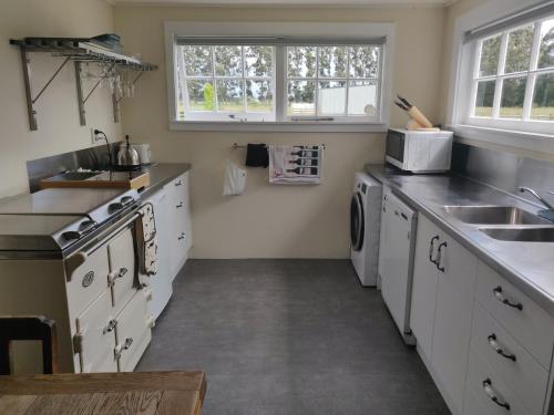 a kitchen with white cabinets and a sink at Bramley's Stables and Accommodation in Rangiora
