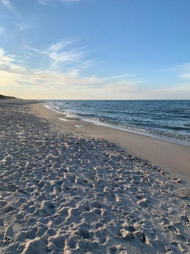 a beach with footprints in the sand and the ocean at Apartament z prywatnym tarasem na dachu Ogień 8 Jurata in Jurata