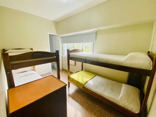 a room with three bunk beds and a table at Hostel Playa Grande Austral in Mar del Plata
