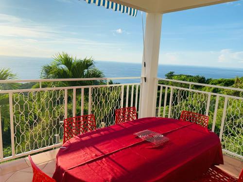 d'une table et de chaises rouges sur un balcon. dans l'établissement PARADIS AU SOLEIL, vue panoramique sur mer, à Bouillante
