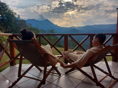 a man and a woman sitting in chairs on a porch at Pousada Portal Dos Ventos in Visconde De Maua