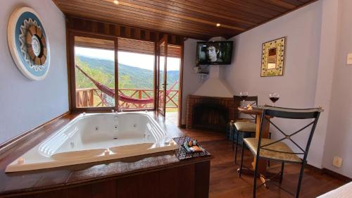 a large bath tub in a room with a view at Pousada Portal Dos Ventos in Visconde De Maua