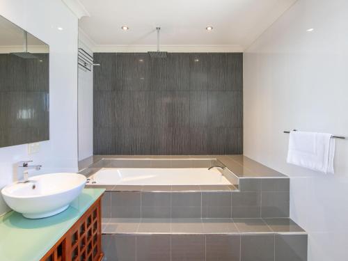 a bathroom with a tub and a sink at Sky Quay 8 in Yamba
