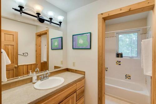 a bathroom with a sink and a mirror and a tub at Hot Tub Cool Views: Roaring Creek Cabin in Leavenworth