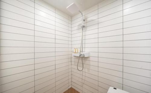a white tiled bathroom with a shower and a toilet at HOTEL701 Masan in Changwon