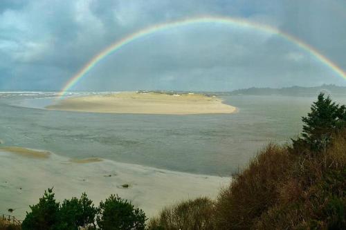 a rainbow over an island in a body of water at Panoramic Promontory: Bay View Beach House in Waldport