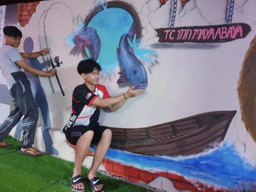 a man sitting in front of a painting of a boat at TC Maya Abaya Hotel in Kuantan