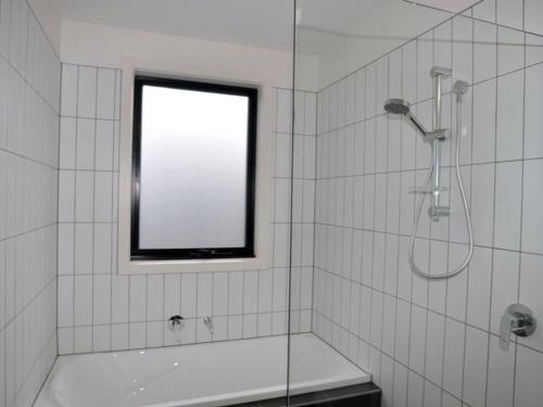 a bathroom with a shower and a tub and a window at Luxe Townhouse 2 in Inverloch