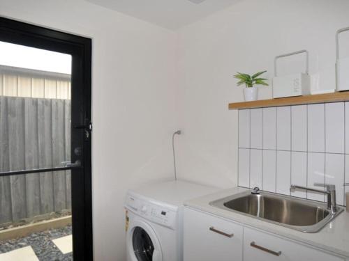 a kitchen with a sink and a washing machine at Luxe Townhouse 2 in Inverloch