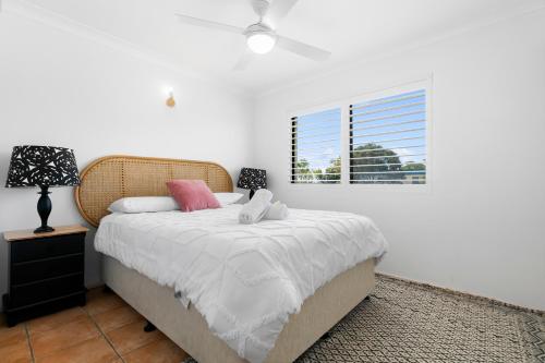 a bedroom with a bed with white sheets and a window at Bayviews at Bongaree in Bongaree