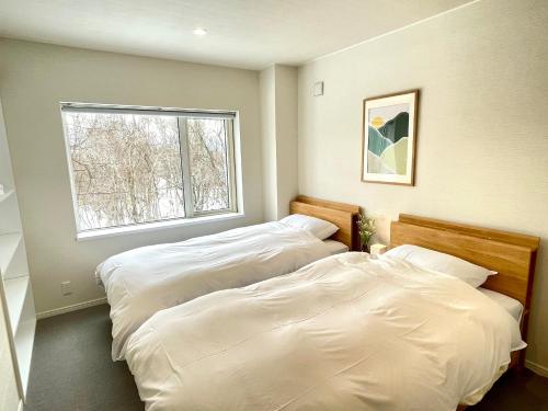 two beds in a room with a window at The Bunker at Yunosato in Rankoshi