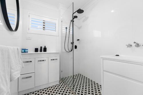 a white bathroom with a shower with a glass door at Bayviews at Bongaree in Bongaree