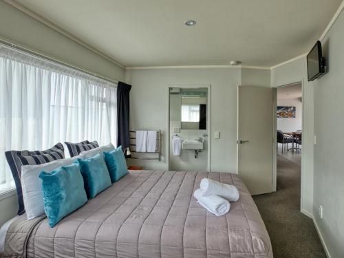 a bedroom with a large bed with blue and white pillows at Ika Nui Taupo in Taupo