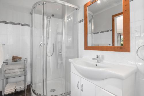a white bathroom with a sink and a shower at Upepo - The Garden Room - Cape Foulwind Studio in Cape Foulwind