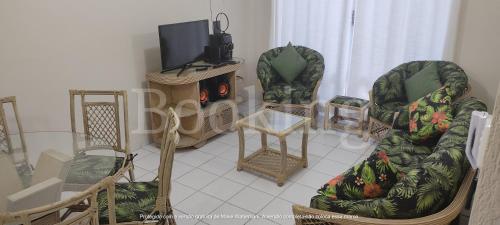 a living room with two chairs and a tv at Apartamento Praia da Enseada in Guarujá