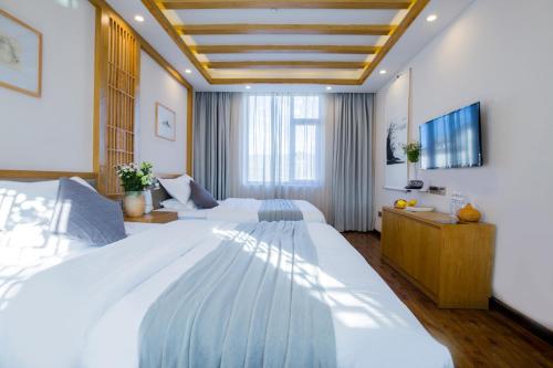 um quarto grande com 2 camas e uma televisão em Lijiang Gemmer Hotel em Lijiang