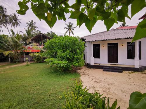 a house with a yard in front of it at Laguna Surfing Stay in Midigama