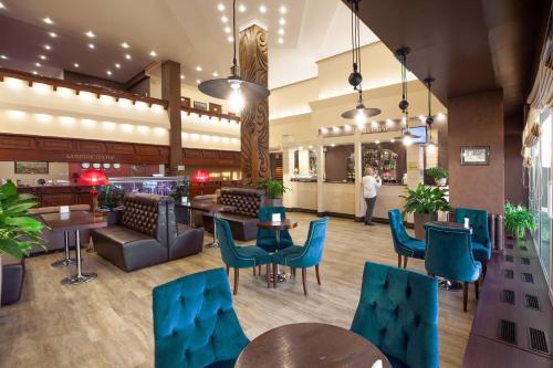 - un hall d'un restaurant avec des tables et des chaises bleues dans l'établissement Hotel Krasnoyarsk, à Krasnoïarsk