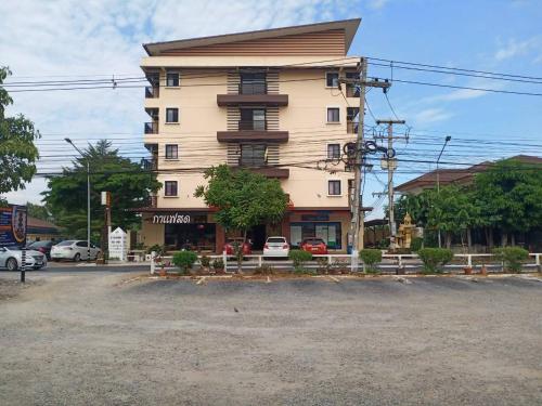 un edificio alto frente a un estacionamiento en โสดาอพาร์ทเม้นท์​ en Ban Lam Phak Kut