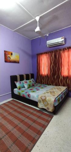 a bedroom with a bed in a room with purple walls at Baiti Homestay in Gambang