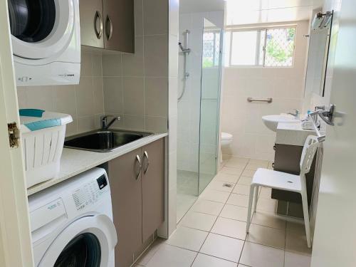 a bathroom with a washing machine and a sink at Park Towers Holiday Units in Gold Coast