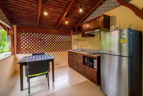 a kitchen with a stainless steel refrigerator and a table at Wandee Garden in Choeng Mon Beach