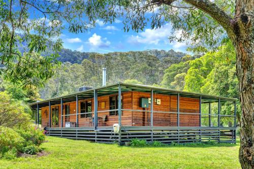 a house in the middle of a field with a tree at Cedar House in Kangaroo Valley