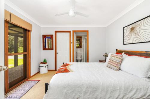 a bedroom with a white bed and a sliding glass door at Cedar House in Kangaroo Valley