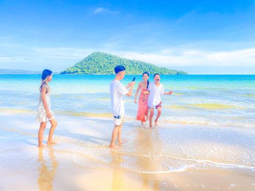 a group of people standing in the water on a beach at Lazy Bones in Koh Rong Sanloem