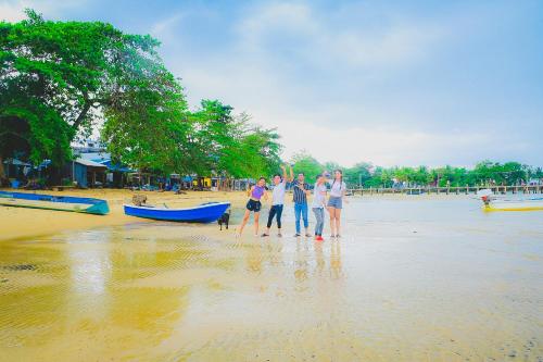 a group of people standing on a beach with a boat at Lazy Bones in Koh Rong Sanloem