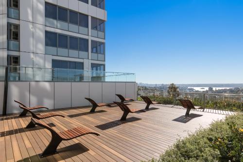a row of benches sitting on a deck in front of a building at Meriton Suites Bondi Junction in Sydney