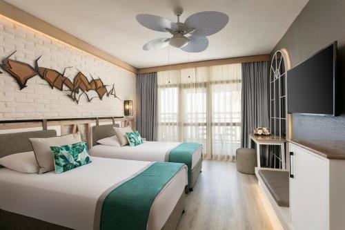 a hotel room with two beds and a flat screen tv at Limak Arcadia Sport Resort Belek in Belek