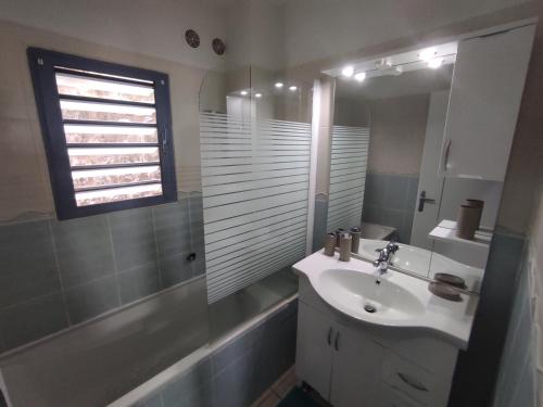 baño con lavabo, ventana y bañera en Charmant appt proche de toutes commodités, en La Possession
