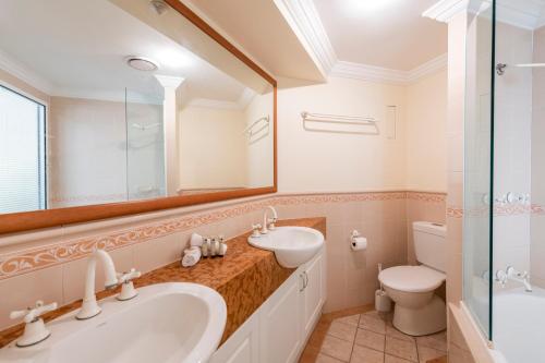 a bathroom with a sink and a toilet and a mirror at Breakers 1 3 LJHooker Yamba in Yamba