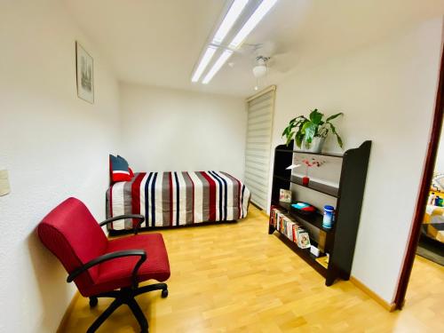 um quarto com uma cadeira vermelha e uma cama em Cómodo y Pintoresco Depa Al sur de La Ciudad! em León